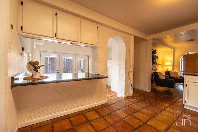 kitchen with dark countertops, visible vents, french doors, arched walkways, and white cabinets