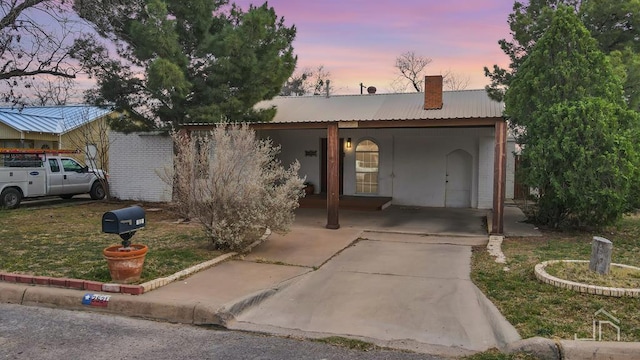 view of front of property with a carport, a chimney, and metal roof