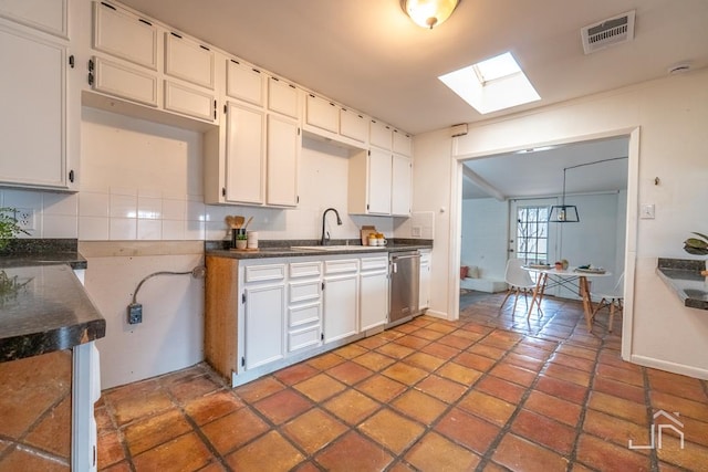 kitchen with visible vents, a skylight, a sink, stainless steel dishwasher, and dark countertops