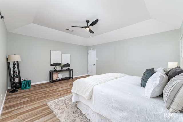 bedroom with a raised ceiling, lofted ceiling, hardwood / wood-style floors, and ceiling fan