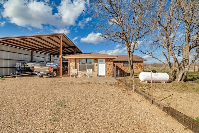 exterior space featuring an outbuilding, brick siding, fence, driveway, and an outdoor structure