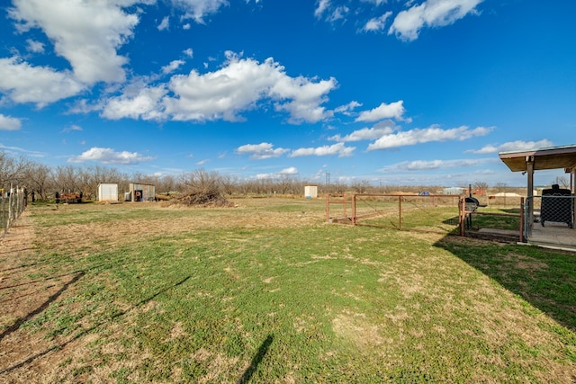 view of yard with a gate, fence, an outbuilding, and a rural view