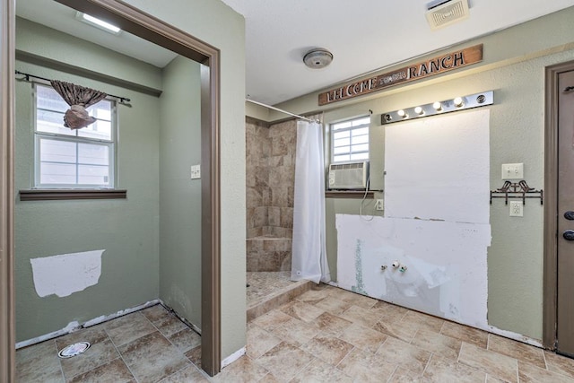 bathroom with stone finish flooring, visible vents, a tile shower, and cooling unit