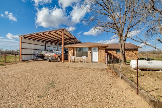 view of front of property featuring driveway, brick siding, and fence