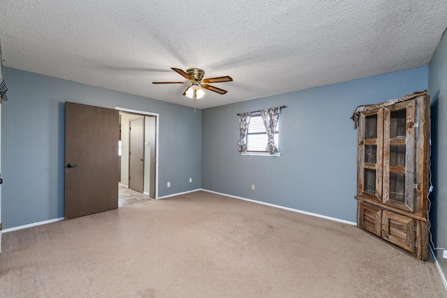 carpeted spare room featuring ceiling fan, baseboards, and a textured ceiling