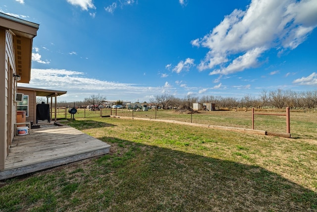 view of yard featuring a wooden deck, fence, and a rural view