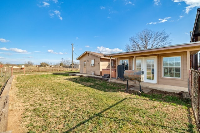 rear view of house with heating fuel, a patio area, fence, and a yard