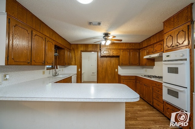 kitchen featuring sink, white appliances, ceiling fan, a textured ceiling, and kitchen peninsula