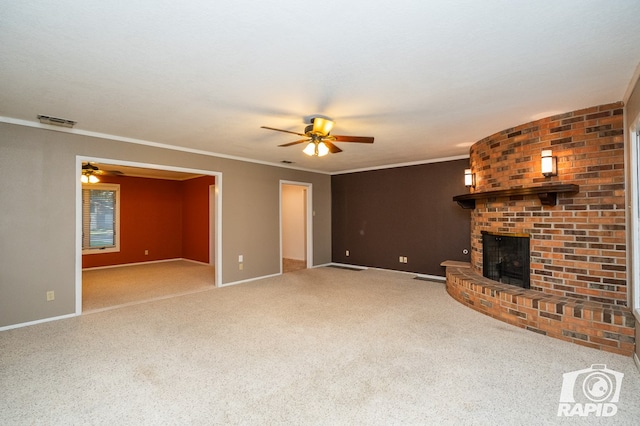 unfurnished living room with a brick fireplace, crown molding, ceiling fan, and carpet flooring