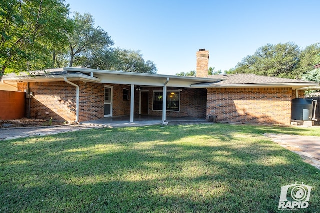 back of property with a yard and a patio area