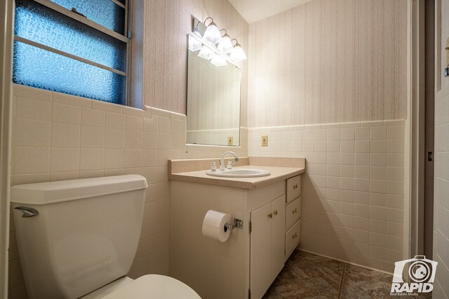 bathroom featuring tile walls, vanity, and toilet