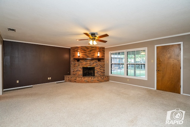 unfurnished living room featuring crown molding, a brick fireplace, carpet floors, and ceiling fan