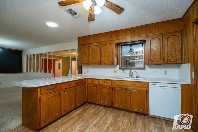 kitchen with dishwasher, sink, kitchen peninsula, a textured ceiling, and light hardwood / wood-style flooring