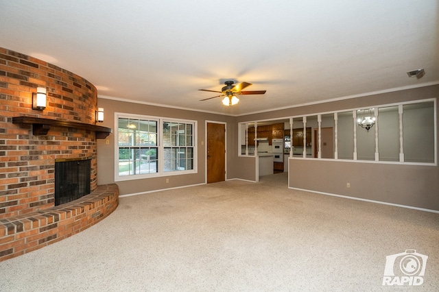 unfurnished living room with ornamental molding, a brick fireplace, carpet, and ceiling fan