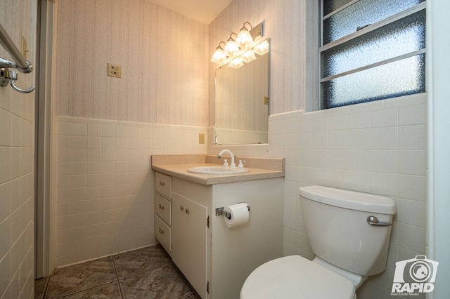 bathroom with vanity, toilet, and tile walls