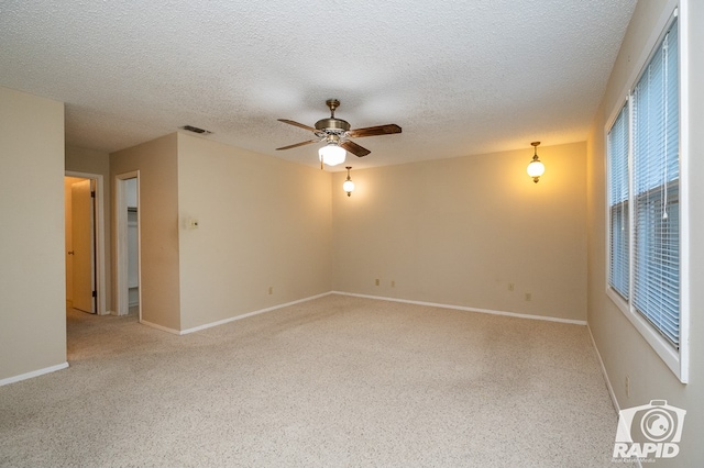 empty room featuring a textured ceiling, light colored carpet, and ceiling fan