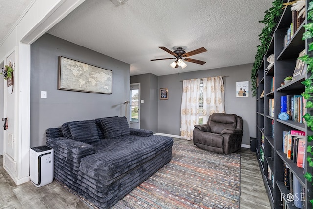 living room featuring hardwood / wood-style flooring, ceiling fan, and a textured ceiling