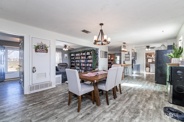 dining area featuring ceiling fan with notable chandelier, hardwood / wood-style floors, and a textured ceiling