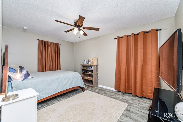 bedroom with ceiling fan, hardwood / wood-style floors, and a textured ceiling