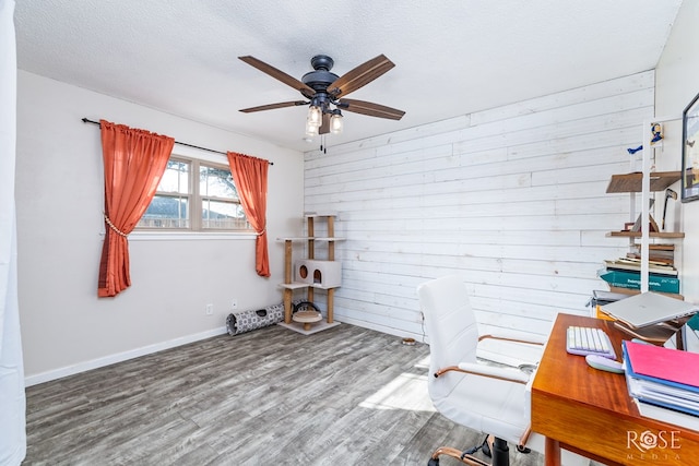 office space with hardwood / wood-style floors, wood walls, a textured ceiling, and ceiling fan