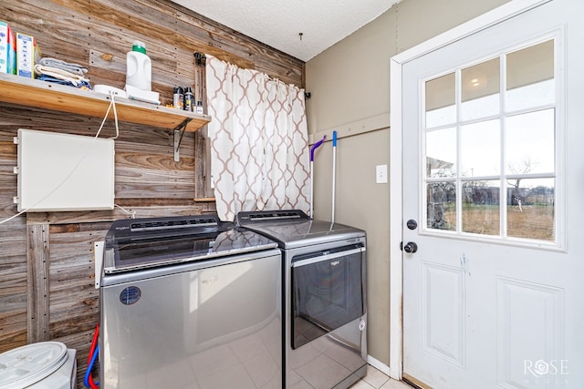 laundry area with light tile patterned floors, a textured ceiling, and washing machine and clothes dryer