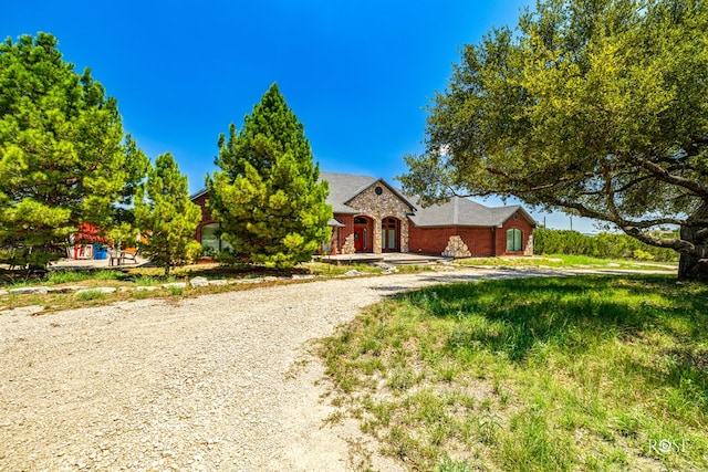 view of front of home featuring gravel driveway and brick siding