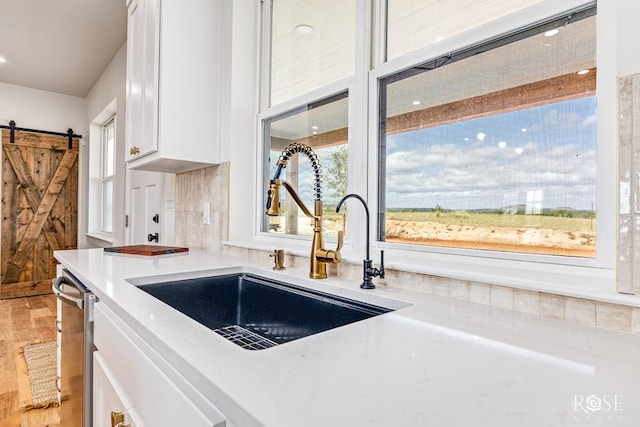 9401 Collett Rd, Robert Lee, TX 76945 - kitchen featuring a barn door, white cabinets, light wood finished floors, stainless steel dishwasher, and light stone countertops