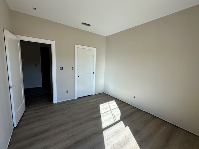 unfurnished bedroom featuring visible vents and wood finished floors