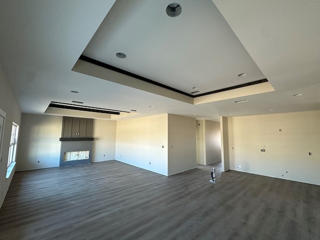 unfurnished living room featuring a tray ceiling, dark wood-style flooring, and a fireplace