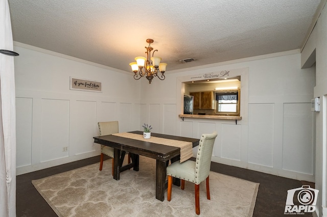 1016 N Adams Ave, San Angelo, TX 76901 - dining space with an inviting chandelier, a textured ceiling, a decorative wall, and visible vents
