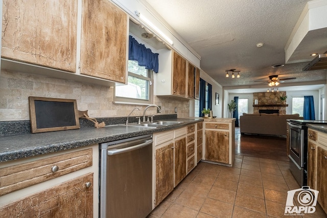 1016 N Adams Ave, San Angelo, TX 76901 - kitchen with dark countertops, a fireplace, a textured ceiling, stainless steel appliances, and tasteful backsplash