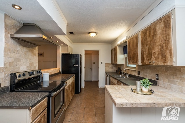 kitchen with freestanding refrigerator, stainless steel range with electric stovetop, tasteful backsplash, a sink, and exhaust hood