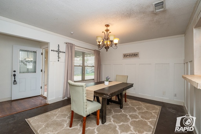 dining space featuring a textured ceiling, visible vents, wainscoting, a notable chandelier, and a decorative wall