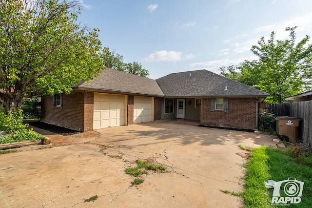 1016 N Adams Ave, San Angelo, TX 76901 - ranch-style house with fence, roof with shingles, an attached garage, brick siding, and concrete driveway