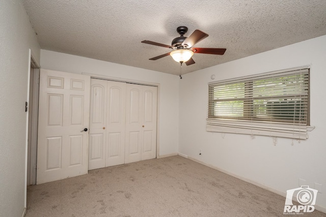 unfurnished bedroom with carpet floors, a textured ceiling, ceiling fan, and a closet
