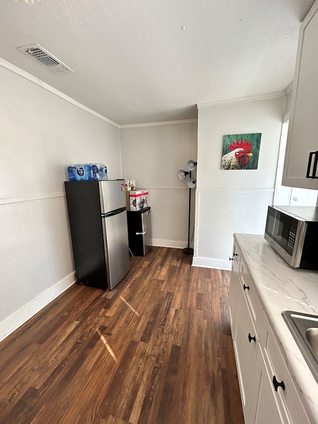 15E 24th St, San Angelo, TX 76903 - kitchen featuring stainless steel appliances, dark wood-style floors, ornamental molding, a textured ceiling, and light stone counters