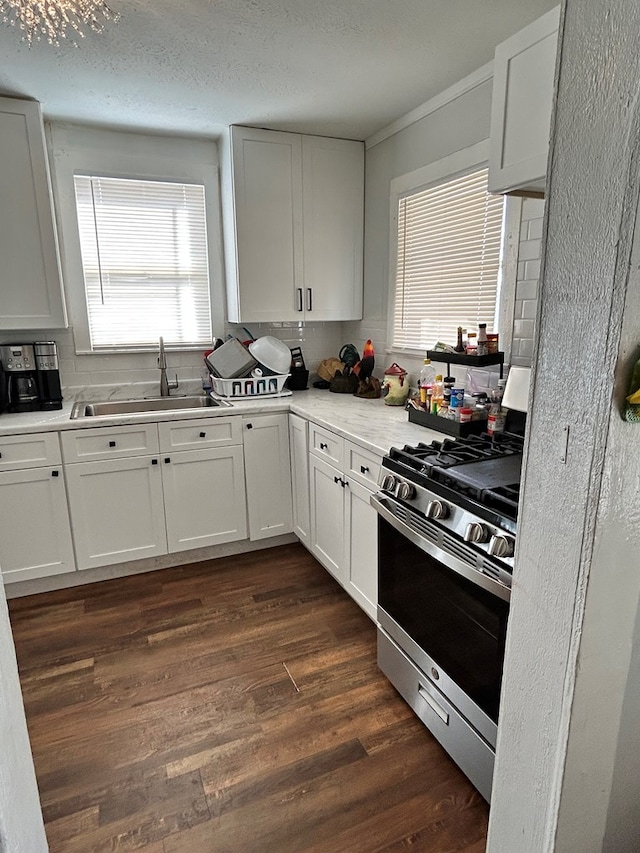 15E 24th St, San Angelo, TX 76903 - kitchen featuring stainless steel range with gas stovetop, tasteful backsplash, dark wood finished floors, white cabinetry, and a textured ceiling