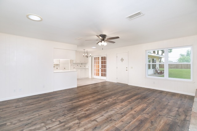 unfurnished living room featuring baseboards, wood finished floors, visible vents, and ceiling fan with notable chandelier