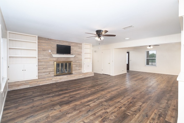 unfurnished living room featuring wood finished floors, a ceiling fan, visible vents, built in features, and a large fireplace