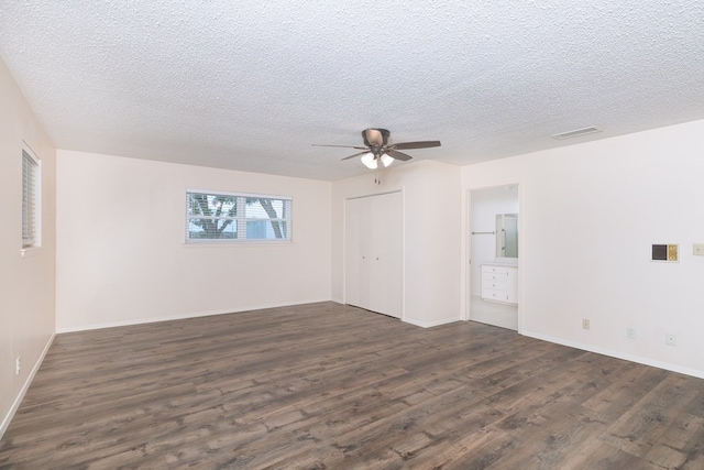 empty room with ceiling fan, a textured ceiling, dark wood-style flooring, and visible vents