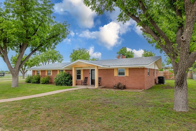 ranch-style home with a chimney, brick siding, fence, central air condition unit, and a front lawn