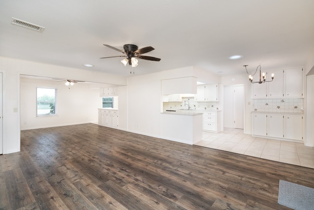unfurnished living room with ceiling fan with notable chandelier, a sink, visible vents, light wood-style floors, and recessed lighting