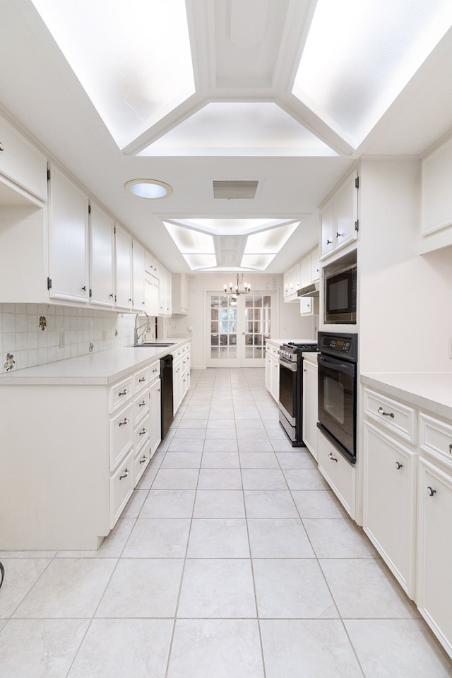 kitchen with white cabinets, light tile patterned floors, black appliances, and a sink