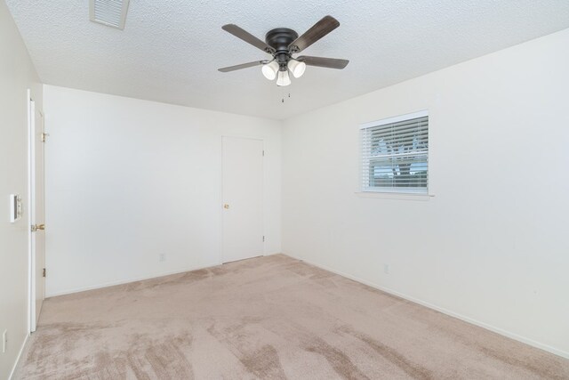 carpeted spare room with a ceiling fan, baseboards, visible vents, and a textured ceiling