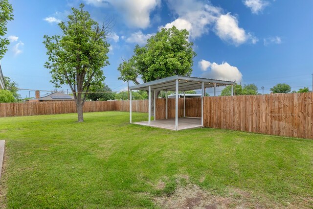 view of yard with a detached carport, a patio area, and a fenced backyard