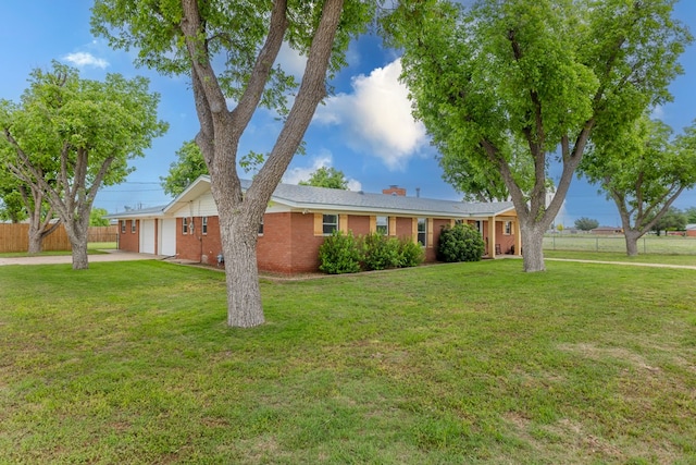 ranch-style home with fence, an attached garage, concrete driveway, a front lawn, and a chimney