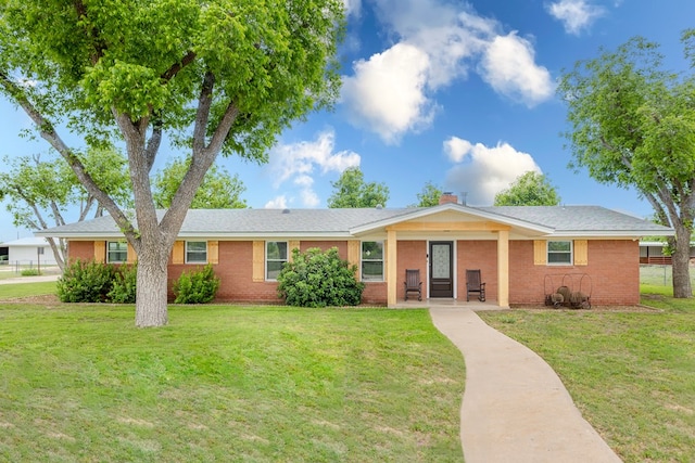 ranch-style house with brick siding, a chimney, and a front yard