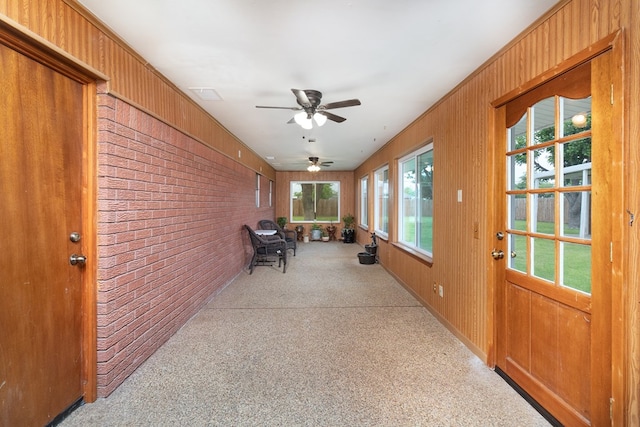 sunroom featuring carpet flooring, wood walls, brick wall, and visible vents