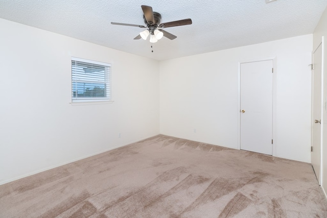 spare room with light carpet, ceiling fan, and a textured ceiling