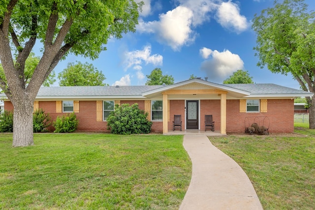 ranch-style home featuring brick siding, a front yard, and a porch